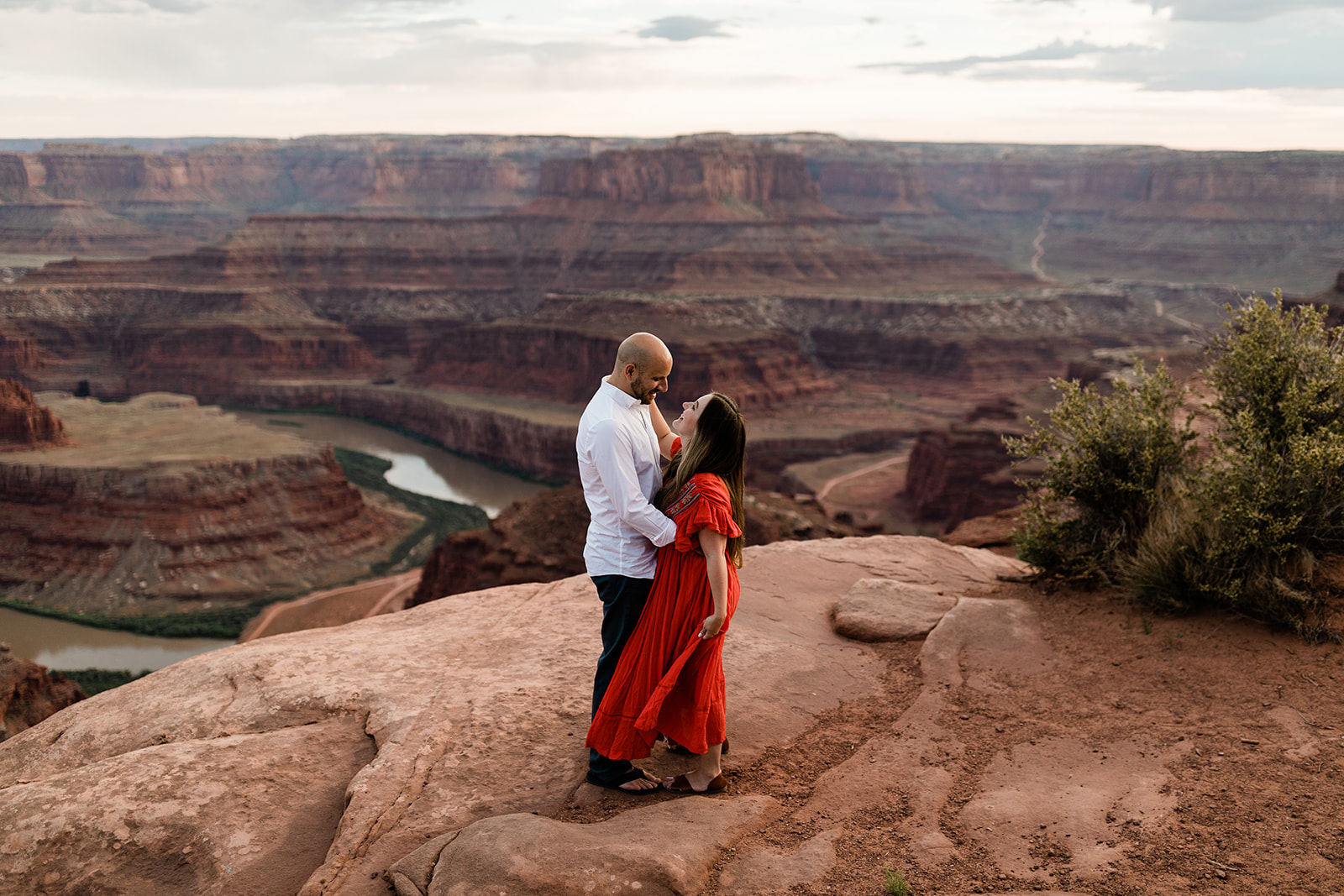 engaged couple hugs and looks out over Moab landscape