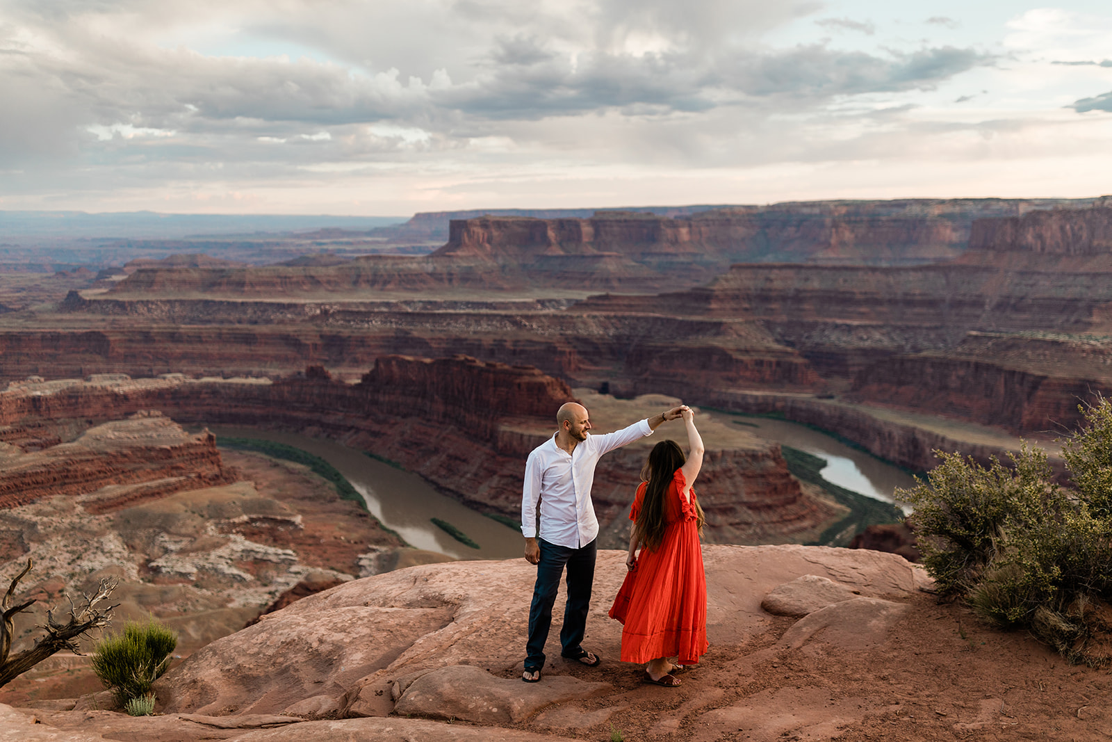 engaged couple dances on top of Moab bluff during adventure photography session with Hazel and Lace Photography