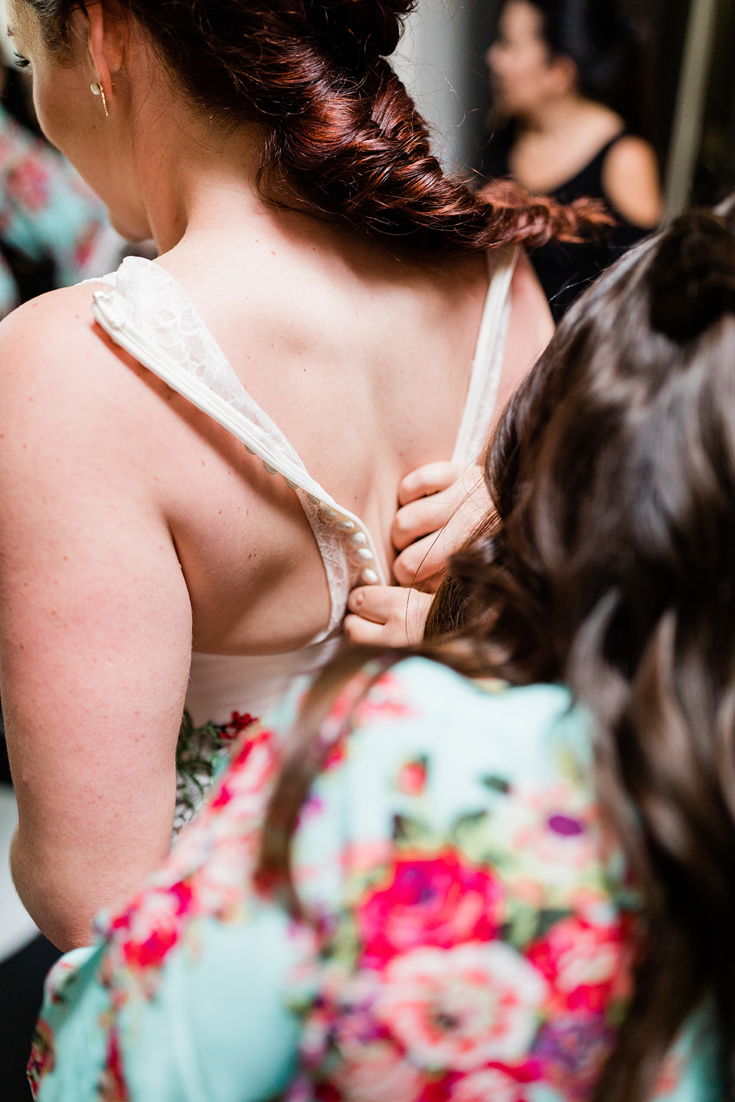 bridesmaids help bride into beautiful designer dress