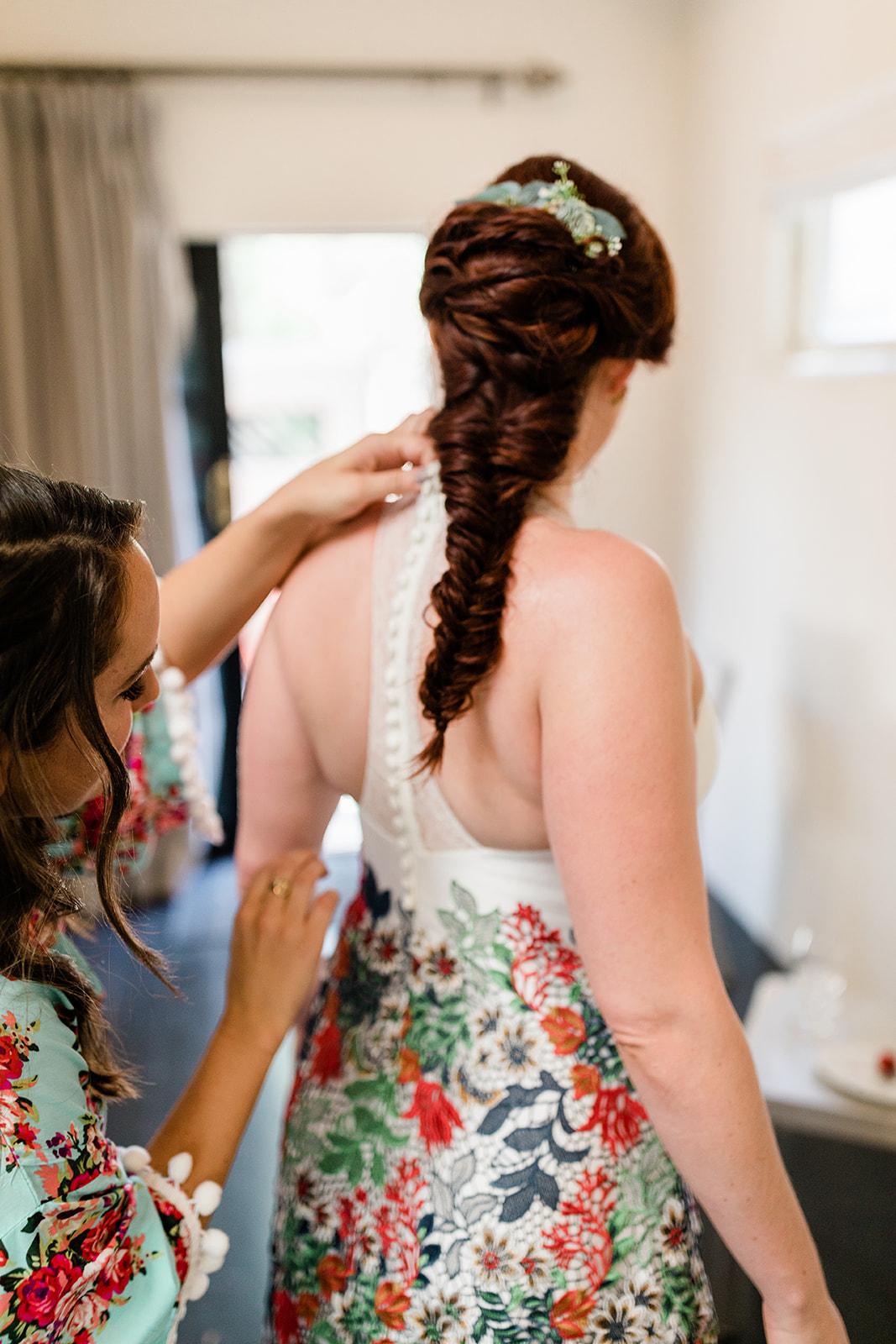 bridesmaids help bride into beautiful designer dress
