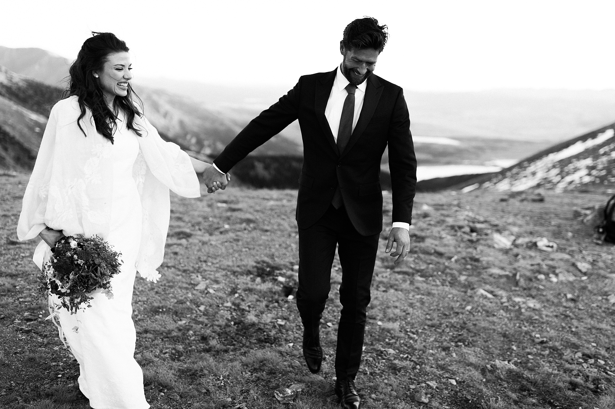 bride and groom walking on mountain top