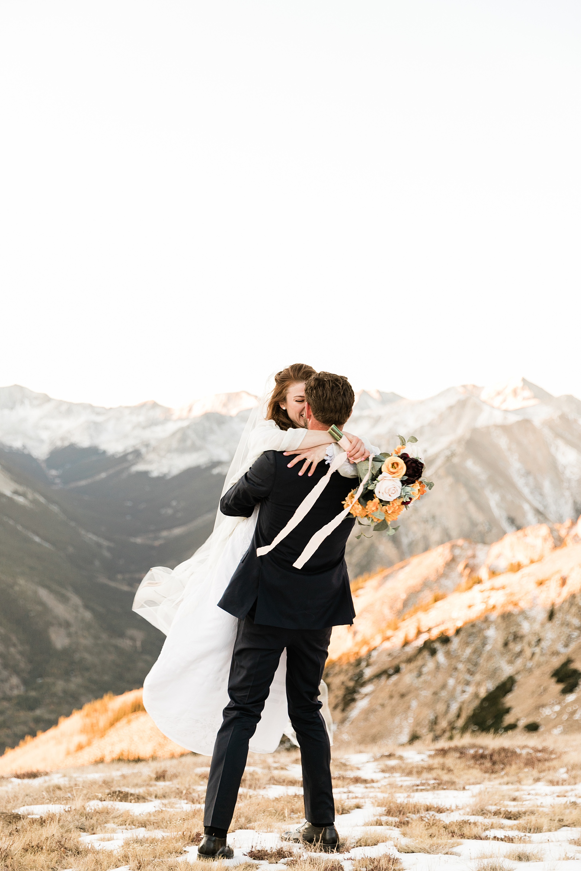 groom twirling bride around on mountain top