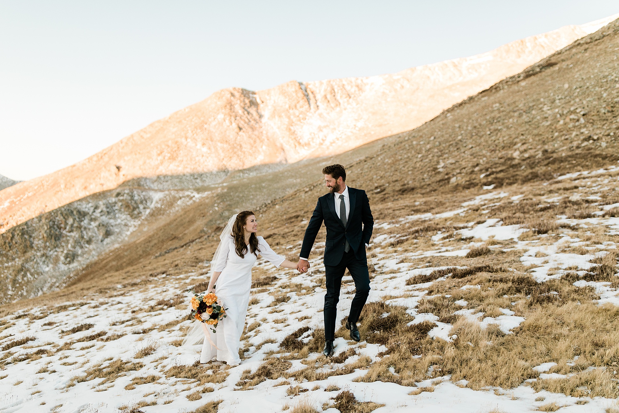 bride and groom walking on mountain top