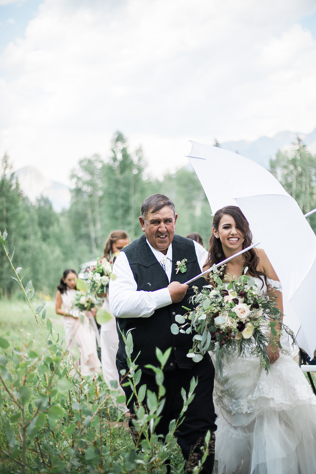 bride and father walk up to aisle with umbrella for outdoor wedding ceremony