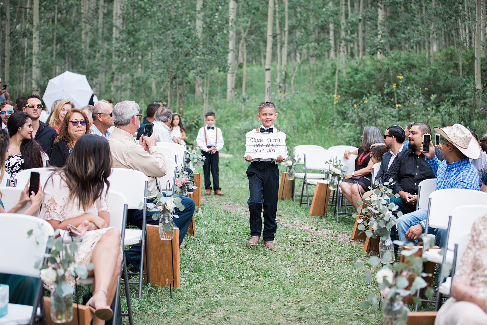 ring bearer walks down the aisle at Silverpick Lodge outdoor Colorado wedding