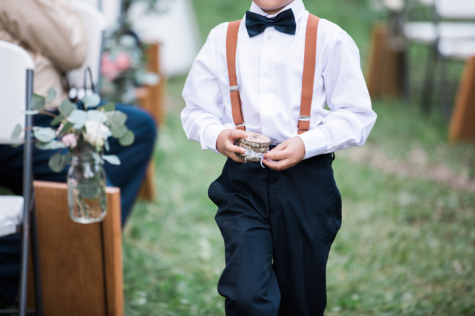 ring bearer walks down the aisle at Silverpick Lodge outdoor Colorado wedding