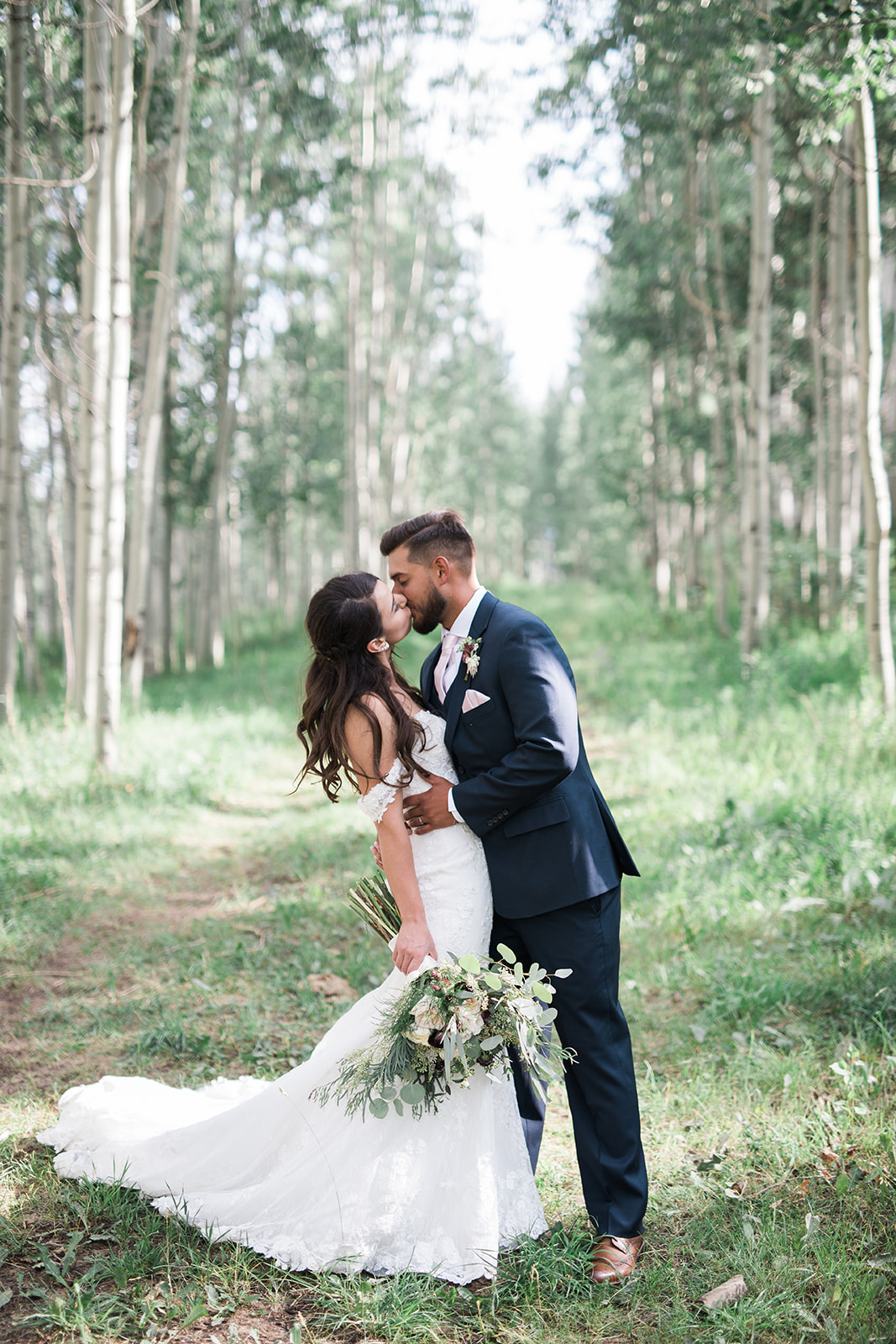 groom kisses bride in alpine woods in Durango Colorado