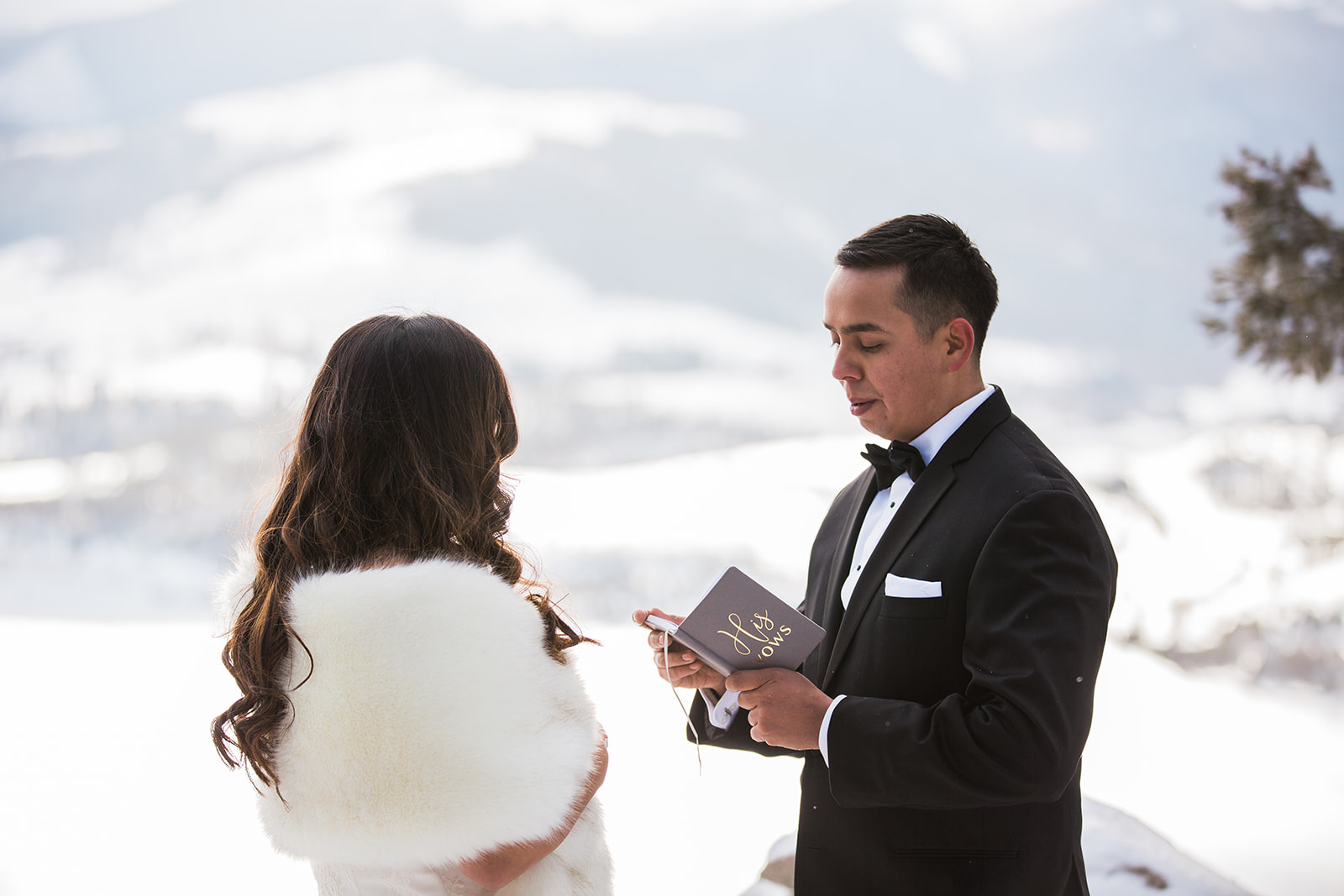 groom reads elopement vows to bride in snowy Colorado mountain elopement