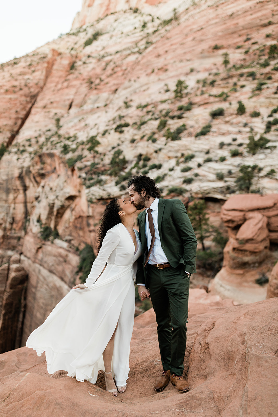 couple kisses in front of Utah red rocks