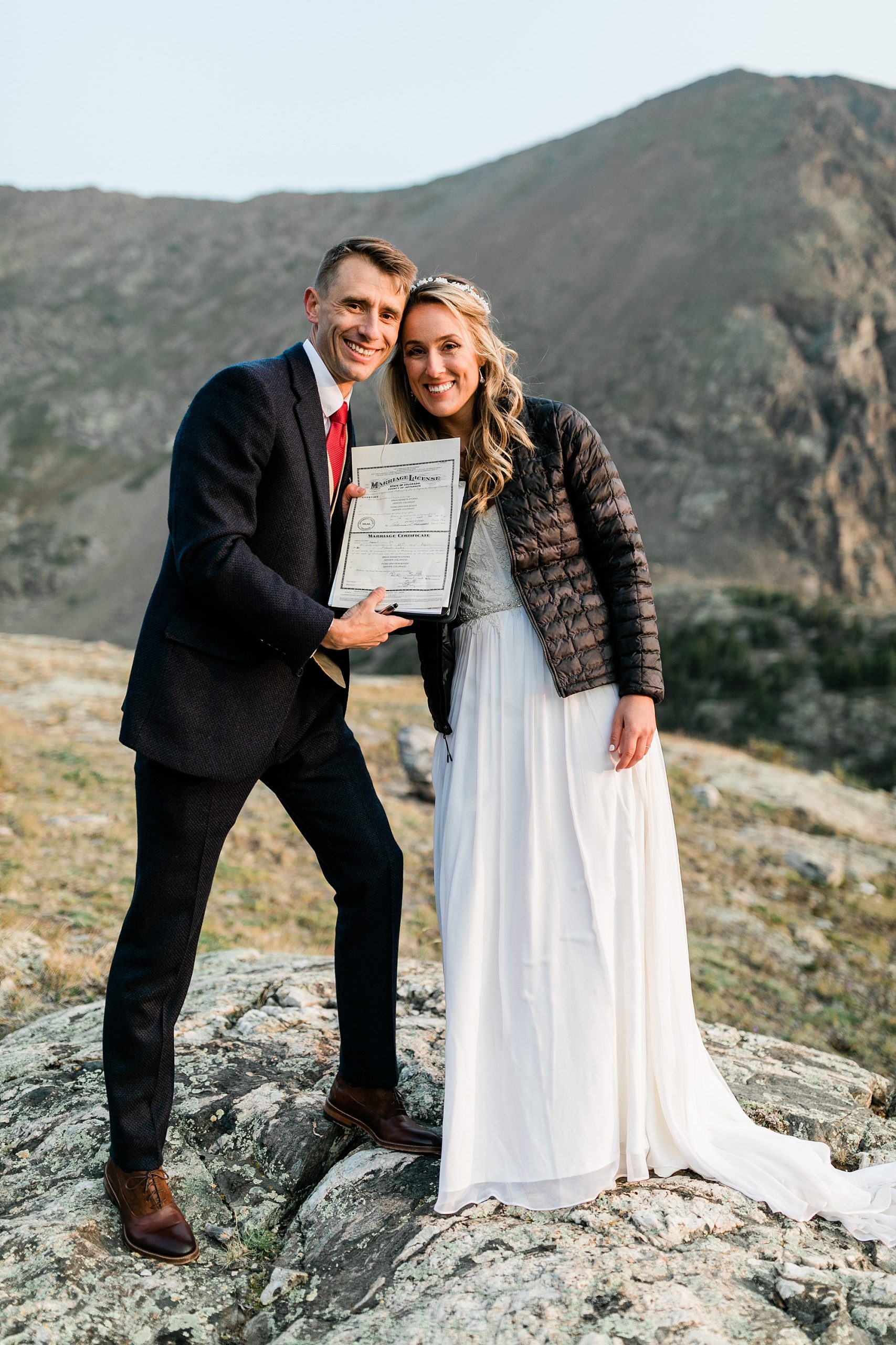 bride and groom pose with marriage license in colorado