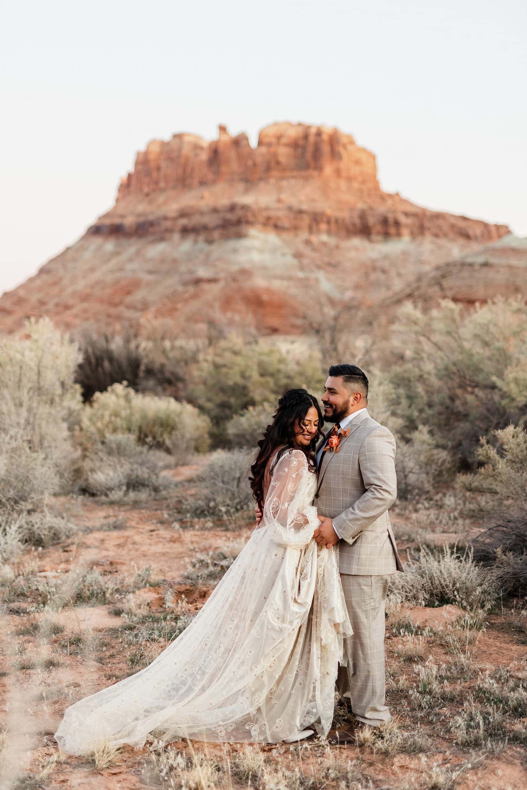 A couple poses after they elope in Moab in front of a red rock structure.