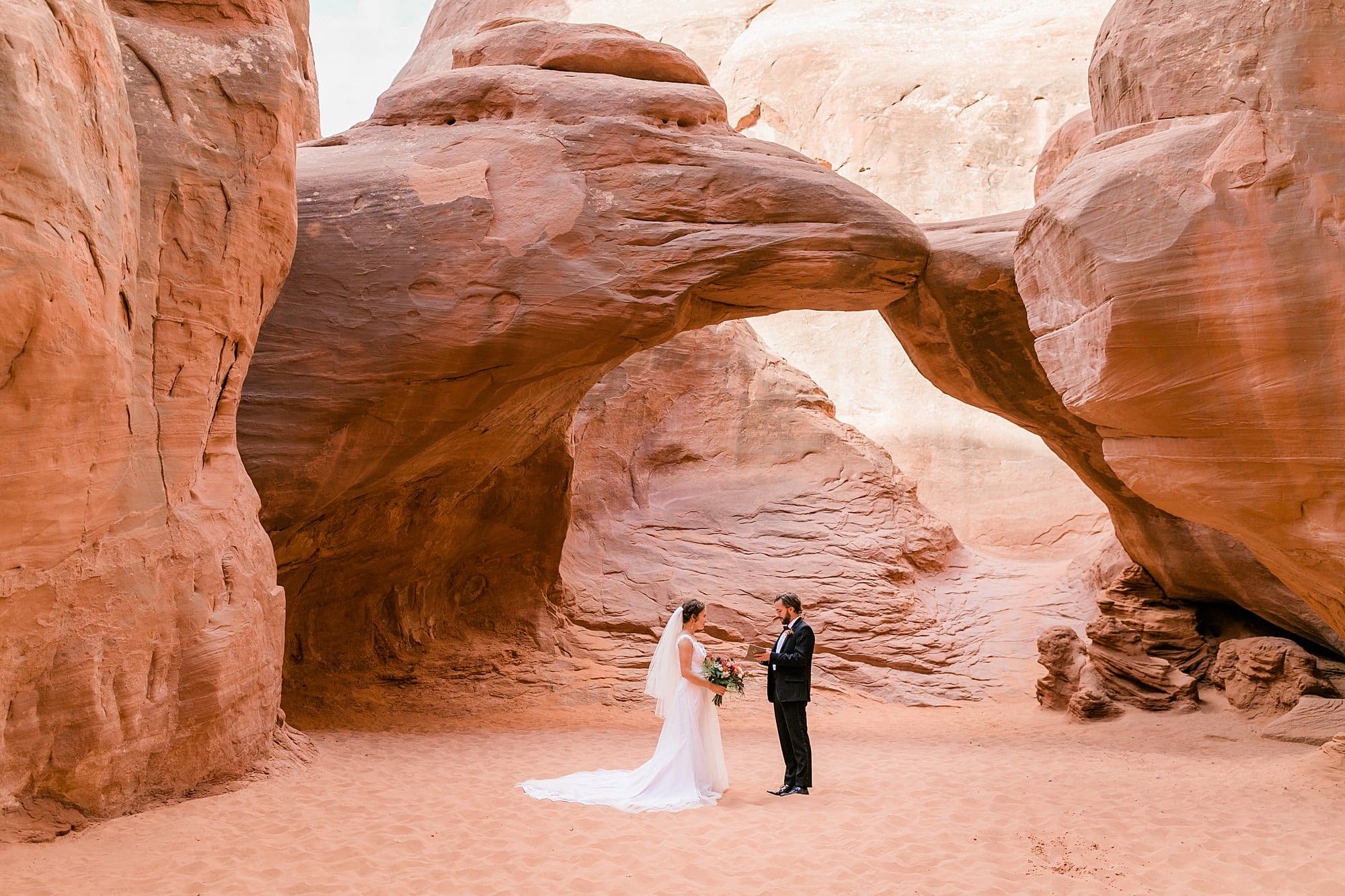 A couple says their vows while they elope in Moab at Sand Dune Arch.