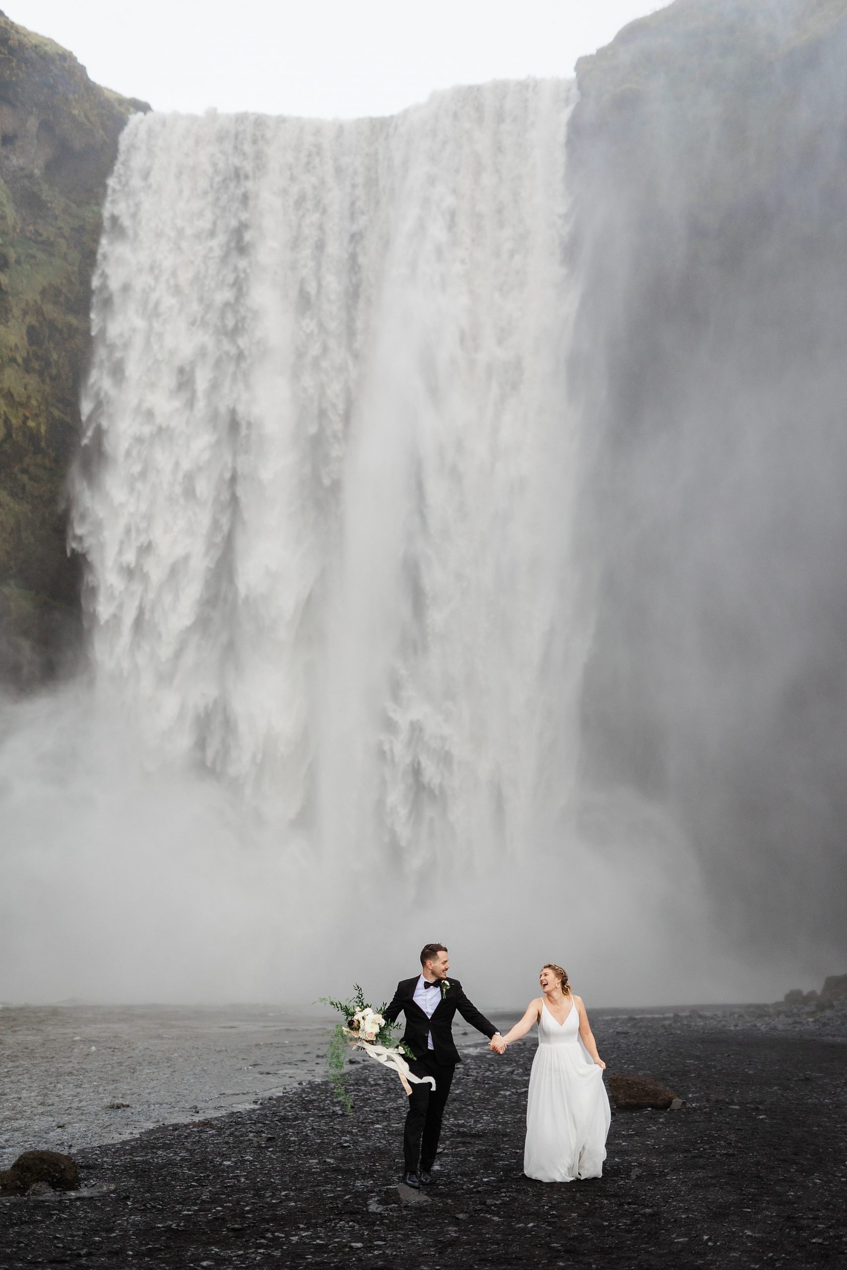 A couple stands in front of Skógafoss as they elope in Iceland