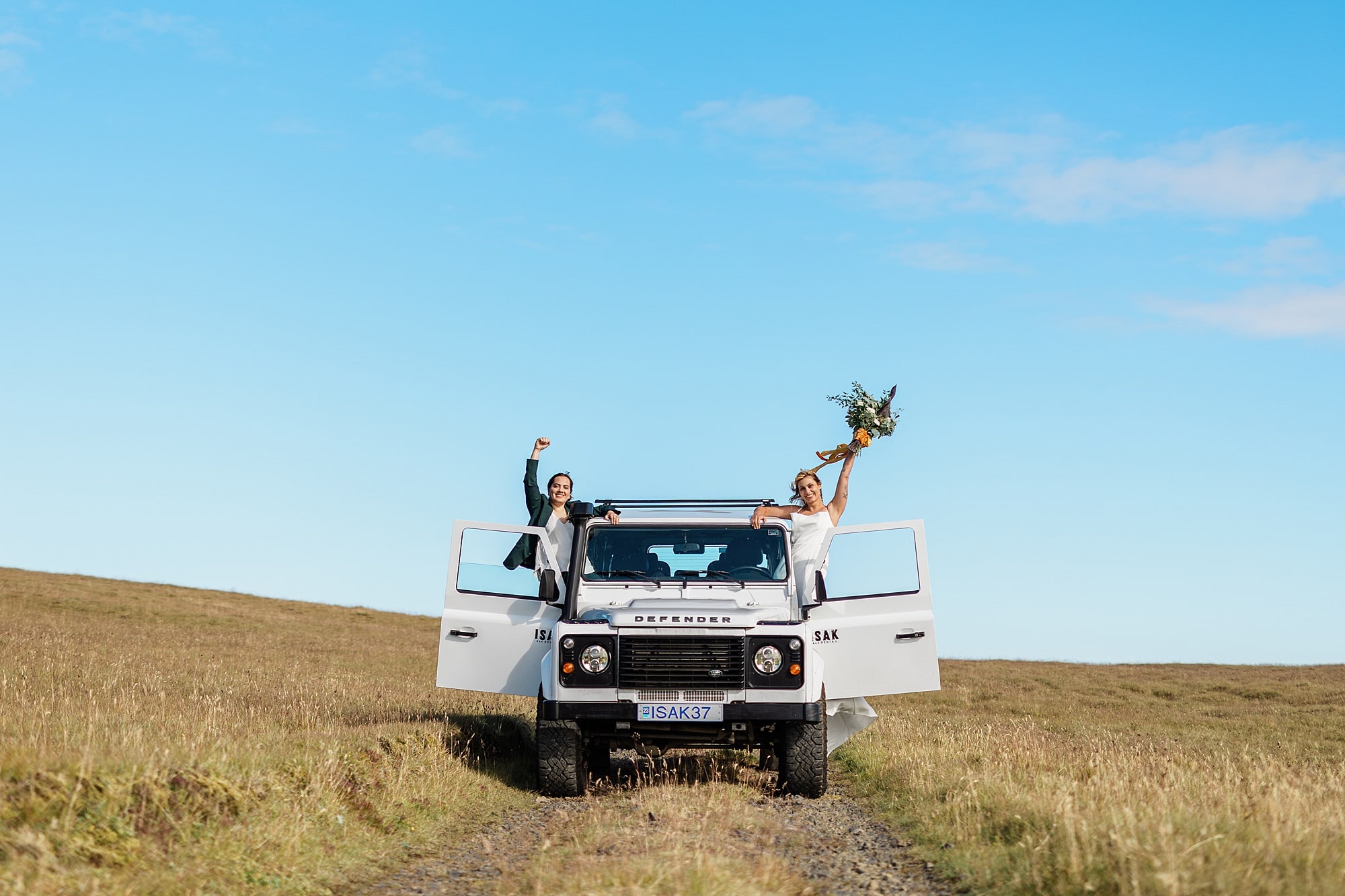 A couple in an off-roading vehicle celebrates in the Icelandic Highlands after they elope in Iceland 