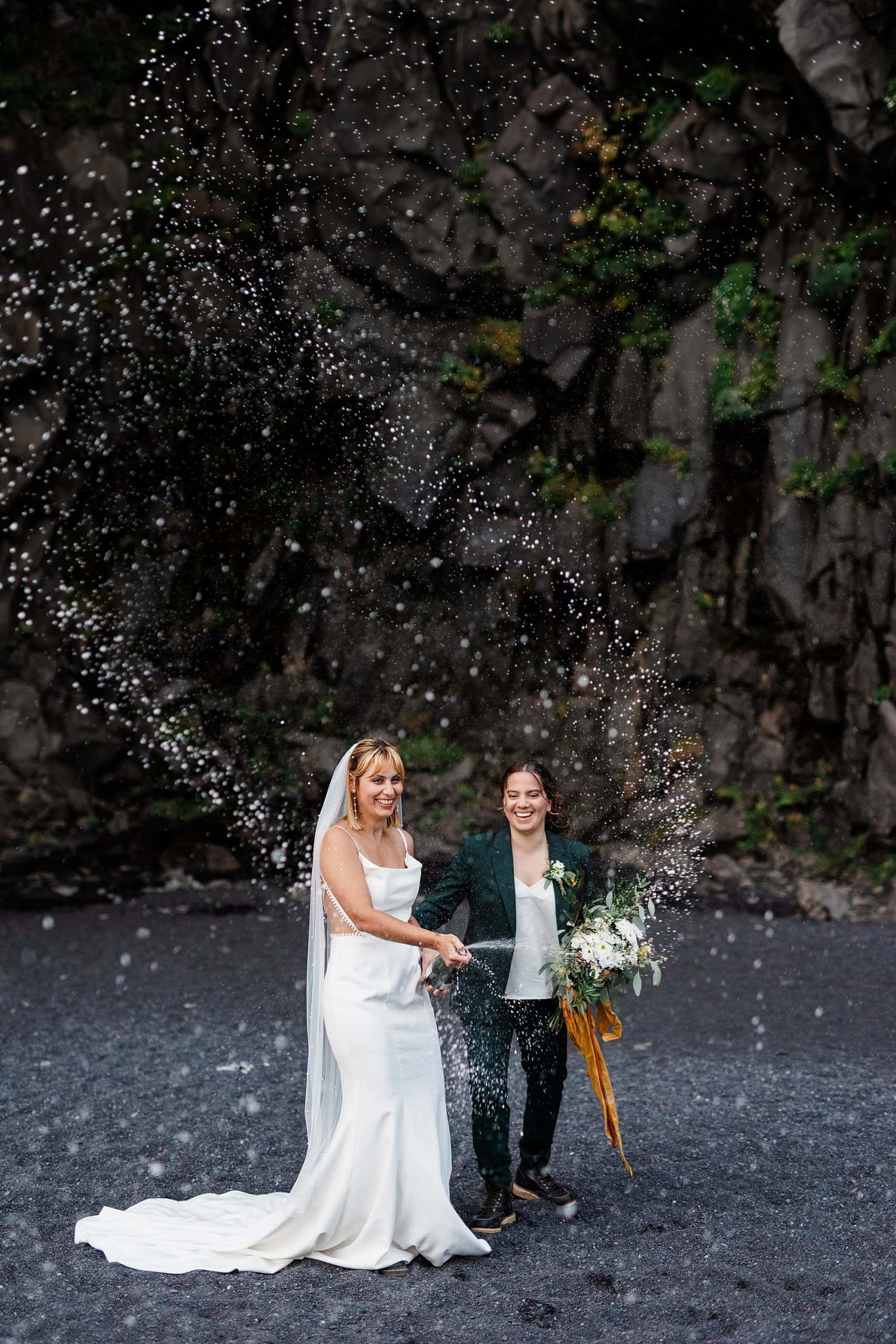 A couple pops champagne on Black Sand Beach in Iceland