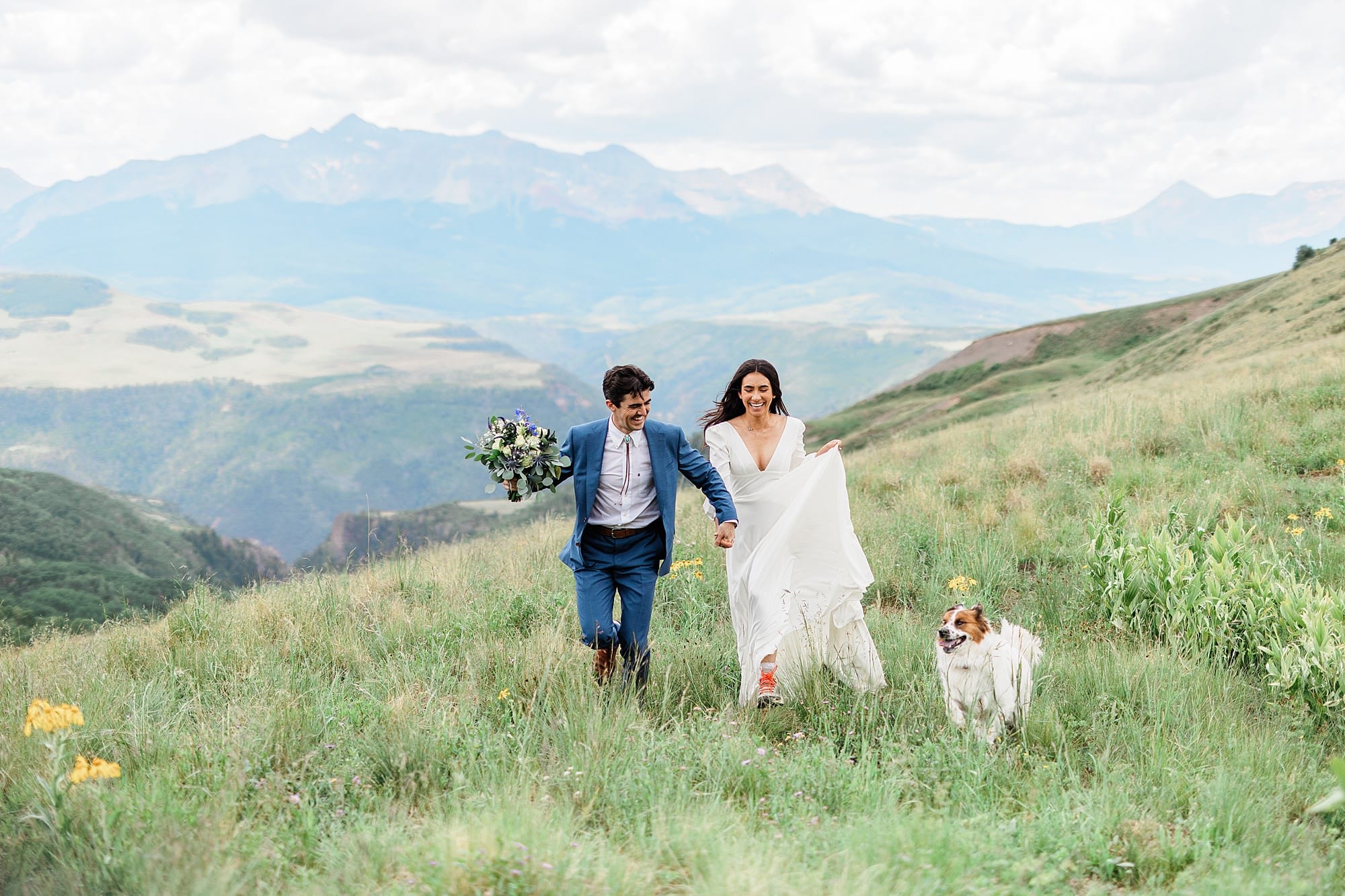 An elopement couple runs with their dog in the mountains of Telluride
