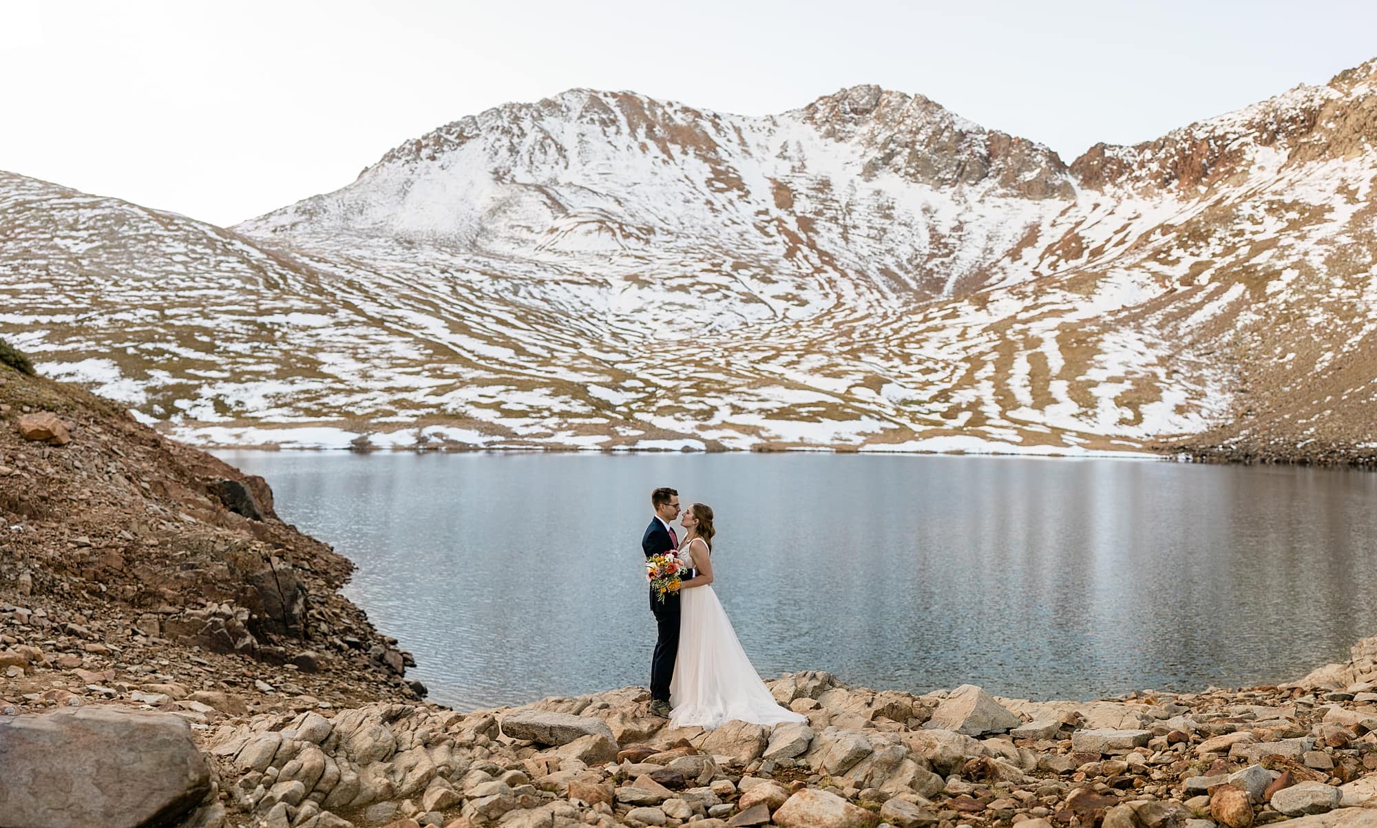 A couple embraces in front of Hope Lake. 