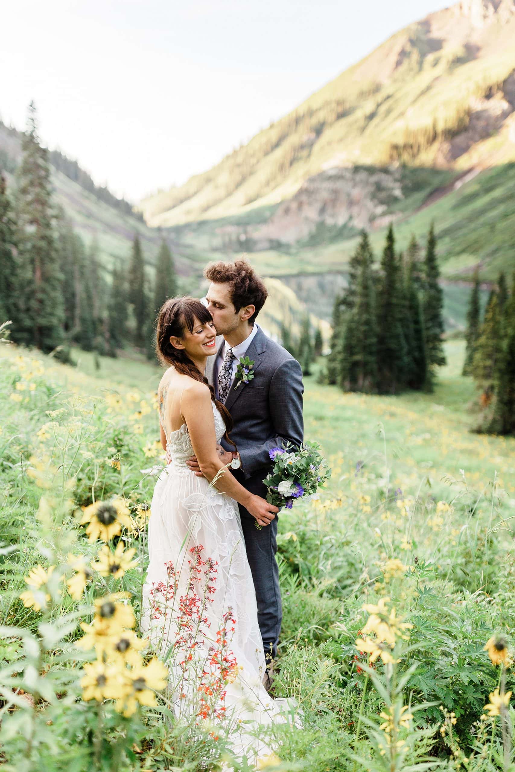 Newlyweds stand in a wildflower field in Colorado after their elopement