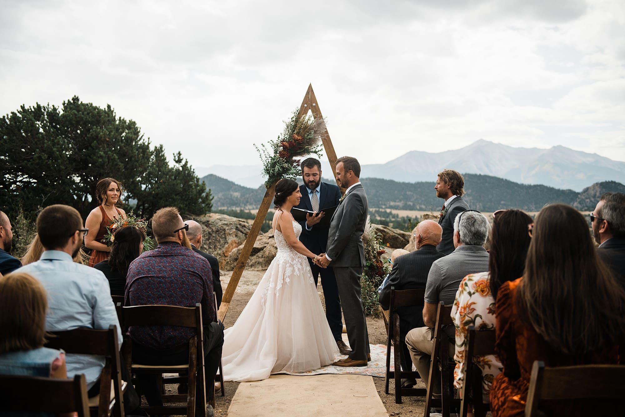 A couple stands in front of a wooden arch during their vow ceremony in Buena Vista, Colorado