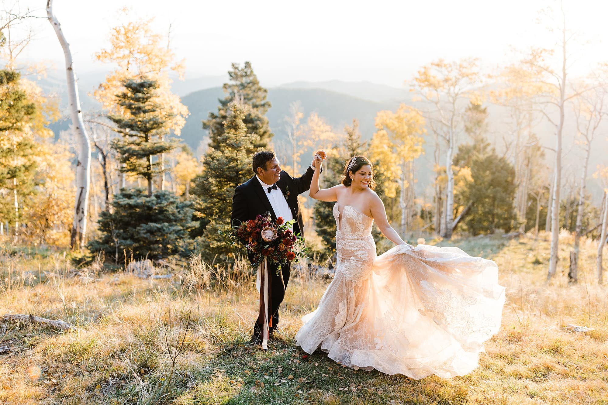 A groom twirls his bride in a forest near Santa Fe