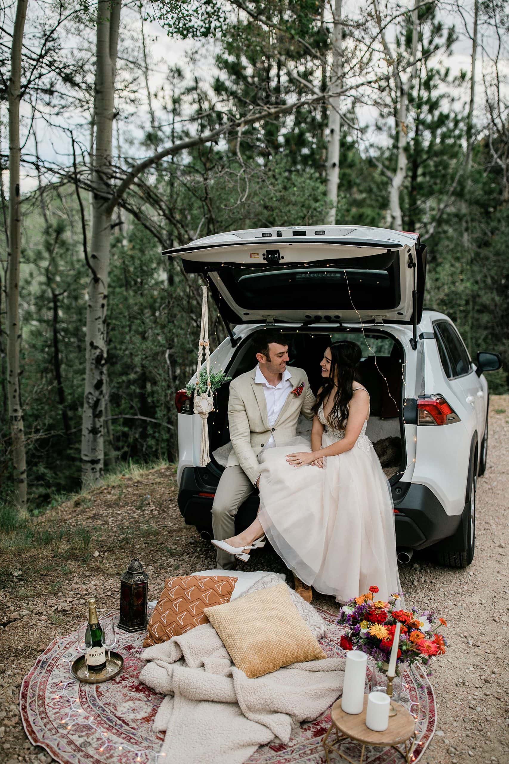 A couple has a picnic in their car for their boho elopement in New Mexico