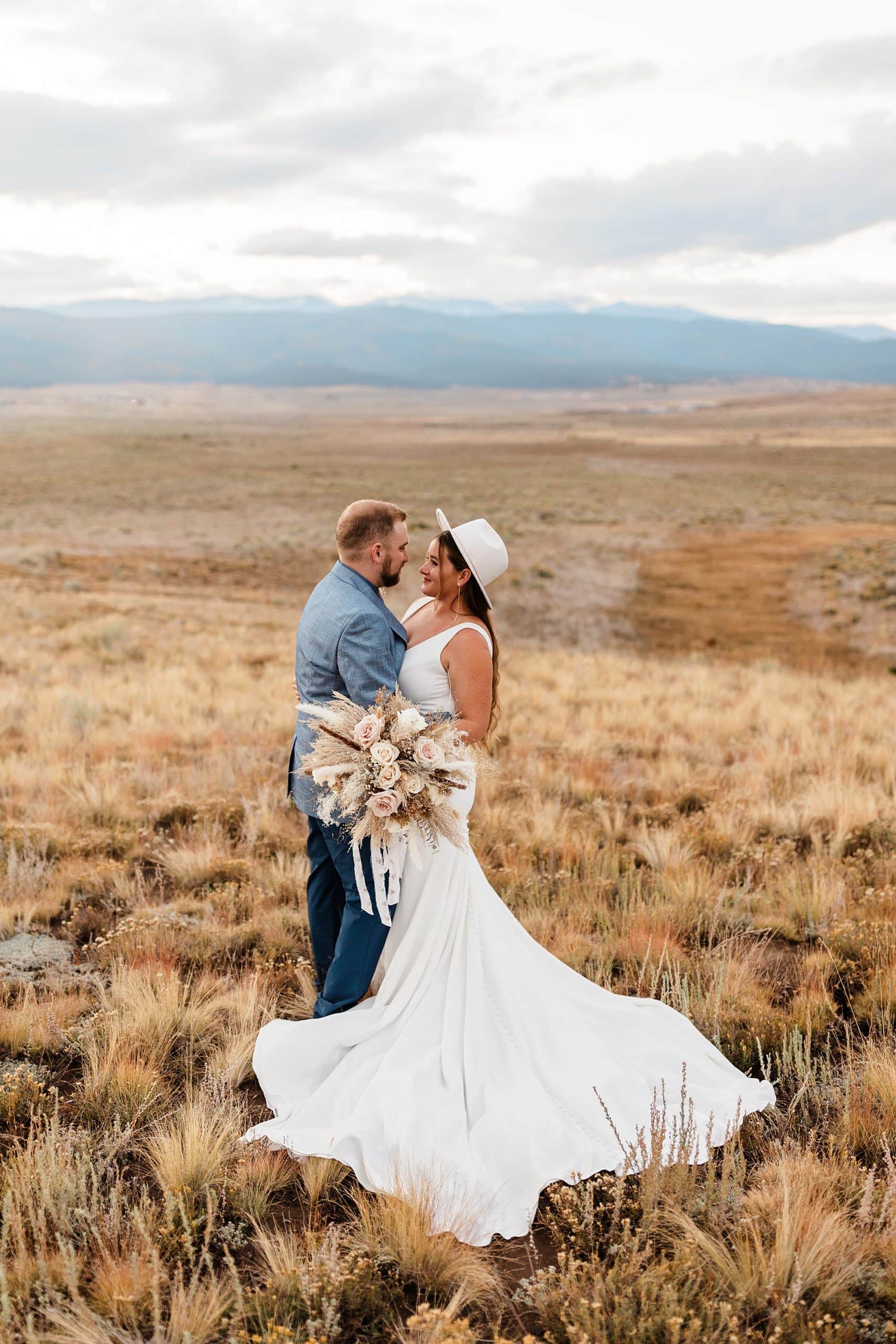 A couple embraces one another while holding dried elopement florals in Taos, New Mexico