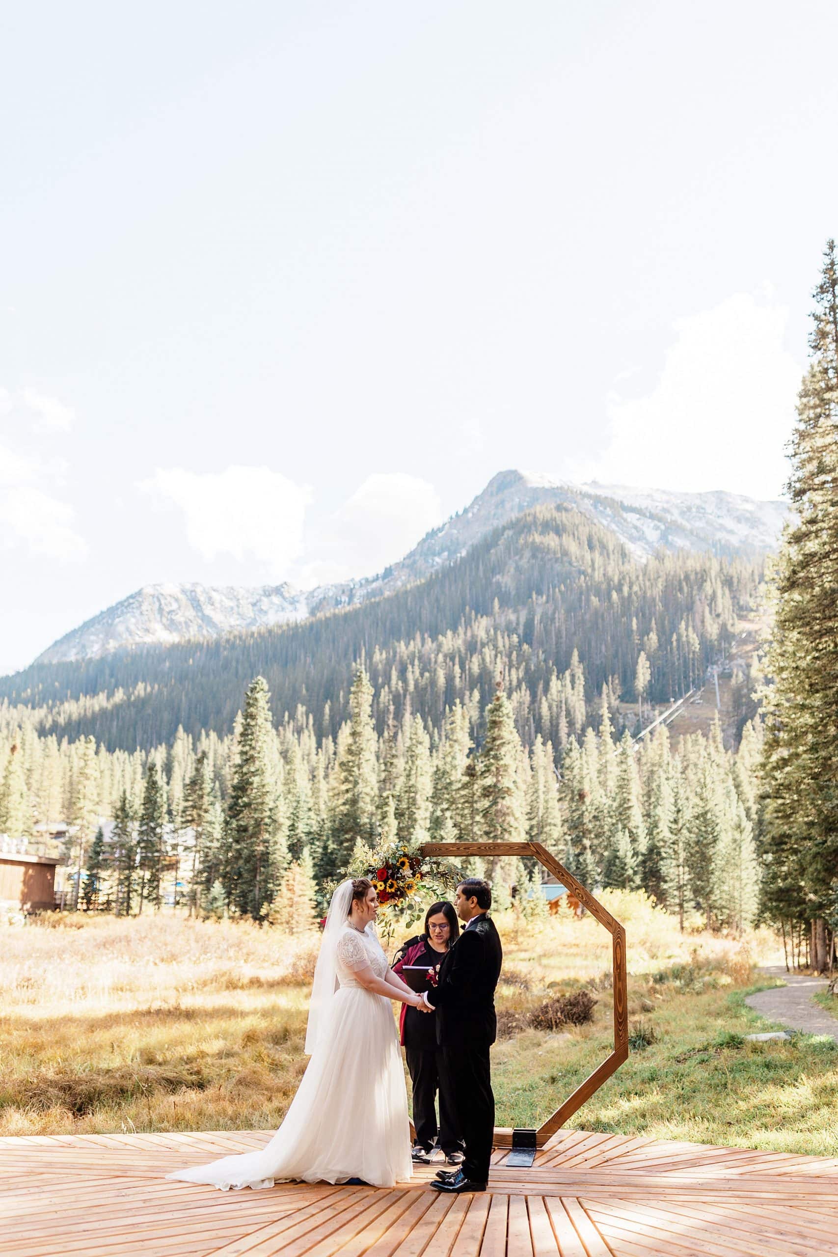 A couple says their vows in front of a wooden arch in Taos Ski Valley