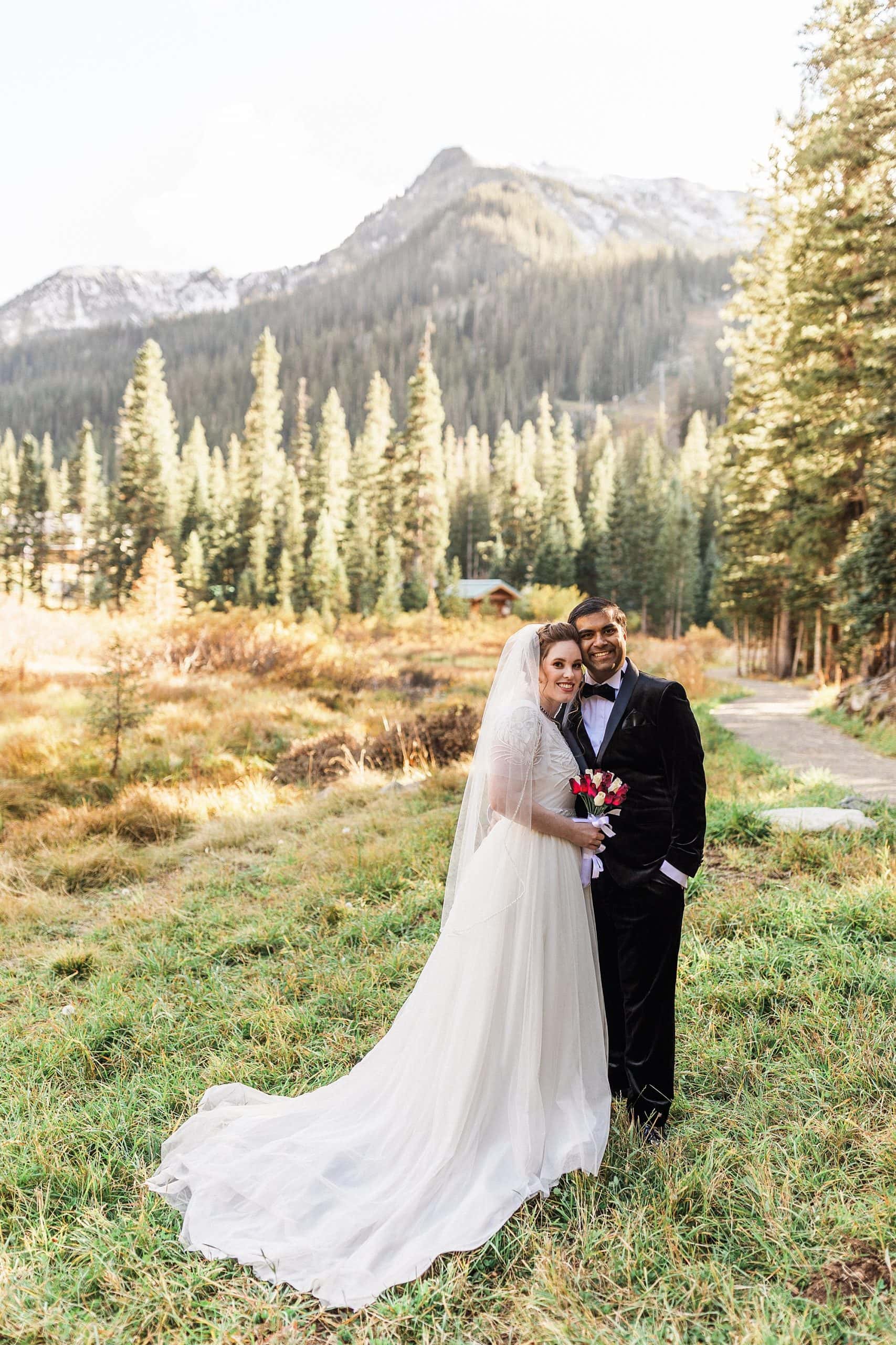 A bride and groom pose for the camera with a mountain in the background in Taos, New Mexico