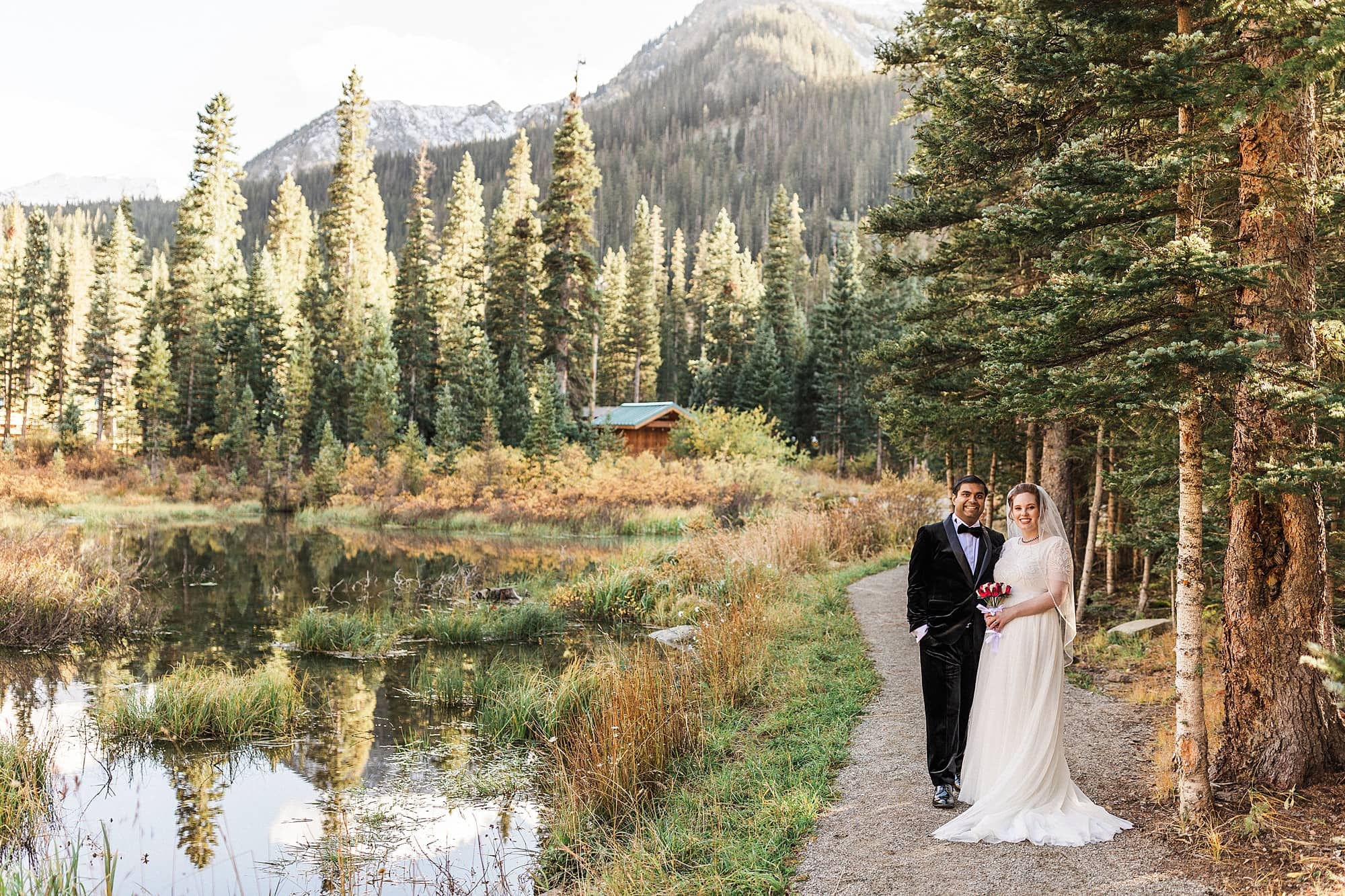 A bride and groom stand in an evergreen forest in Taos Ski Valley