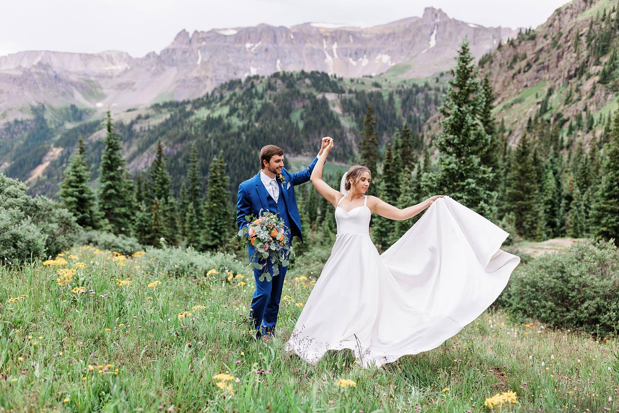 A couple twirls in wildflowers during their elopement hike in the Rocky Mountains