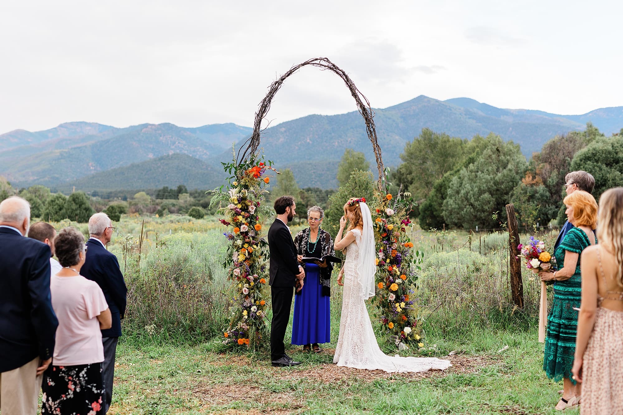 An intimate wedding with a floral arch is being held at Taos Goji Farm.
