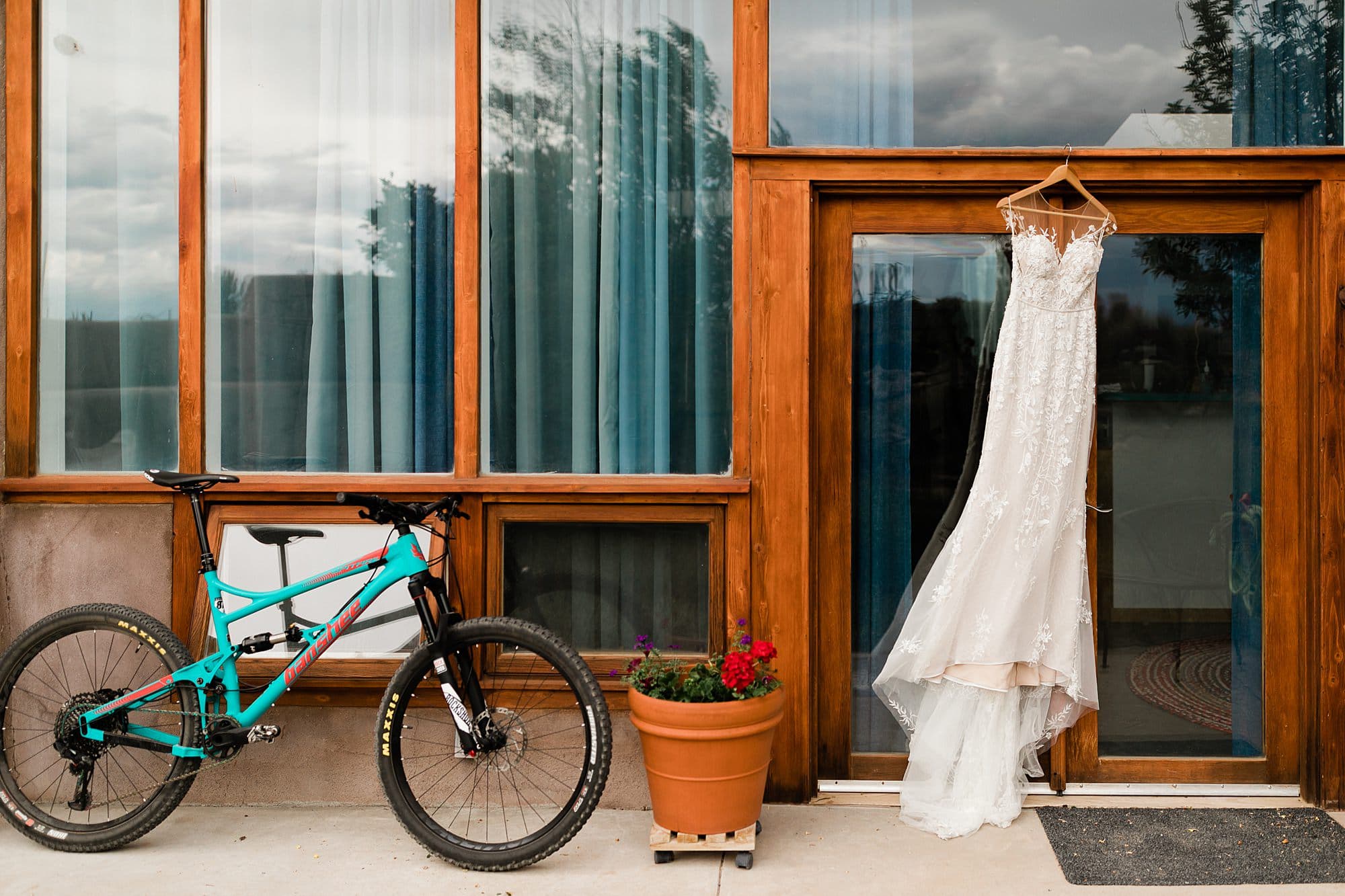 A wedding dress and bicycle accent the architecture of an Earthship in Taos.