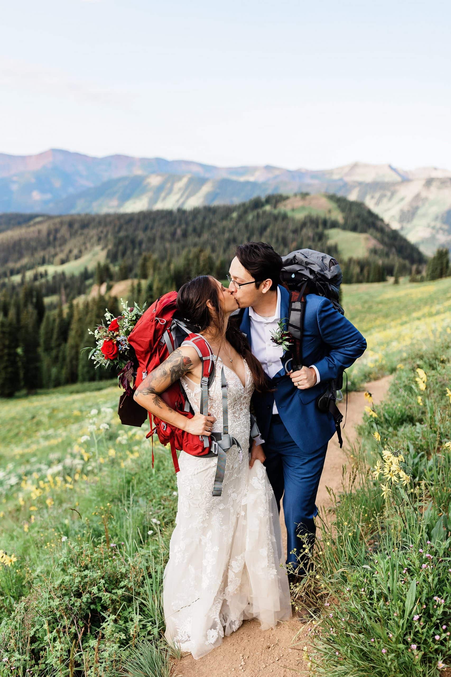 A bride and groom kiss on a mountain top after their hiking elopement